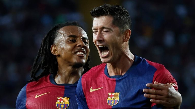 Barcelona's Robert Lewandowski, right, celebrates with Jules Kounde after scoring...