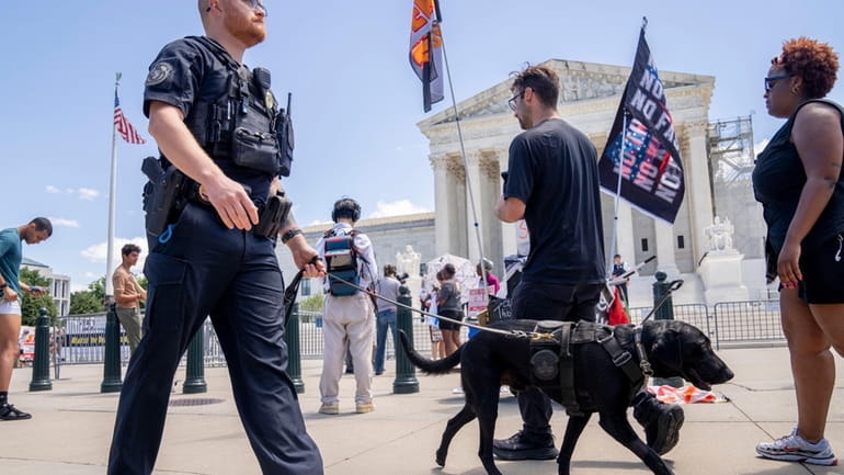A U.S. Capitol Police officer and K-9 patrol pass protesters...