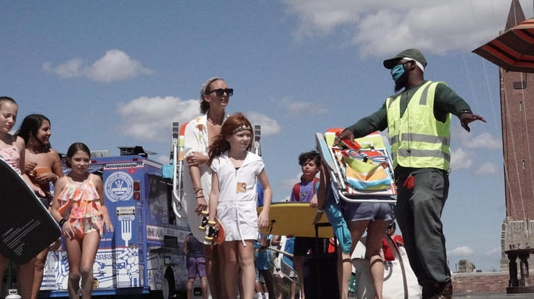 Jones Beach worker Janus Childress, right, of Freeport, reminds visitors Thursday to social...