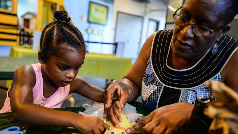 Avery Creary, 3, of Roosevelt, is helped by her grandmother...