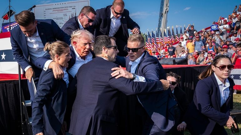 Secret Service agents help former President Donald Trump off the...