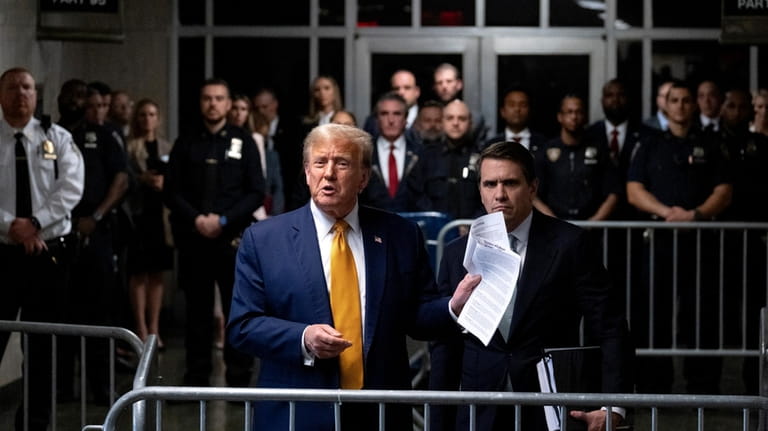 Former President Donald Trump, standing with defense attorney Todd Blanche,...