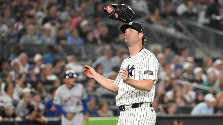 Yankees starting pitcher Gerrit Cole throws his mitt into the...