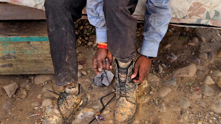 Aamir Shekh puts shoes on before going to work as...
