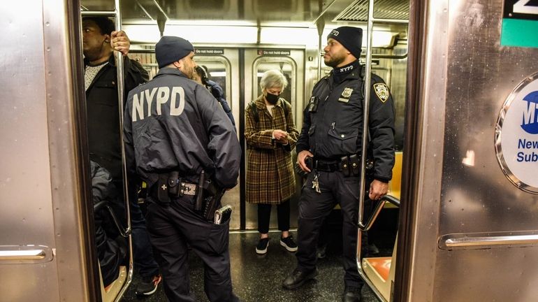 New York City Police Department officers patrol a subway car in...