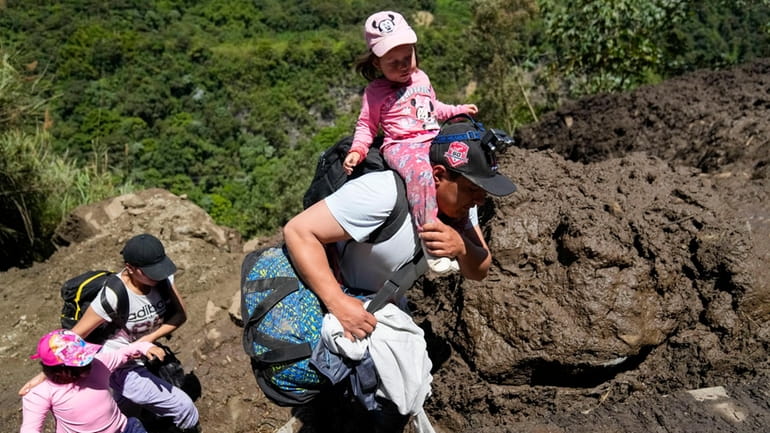 Residents traverse terrain that experienced landslides in Banos, Ecuador, Monday,...