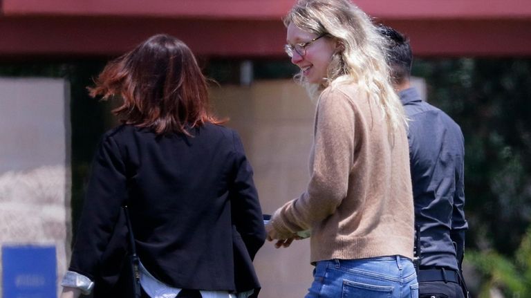 Former Theranos CEO Elizabeth Holmes, center, is escorted by prison...