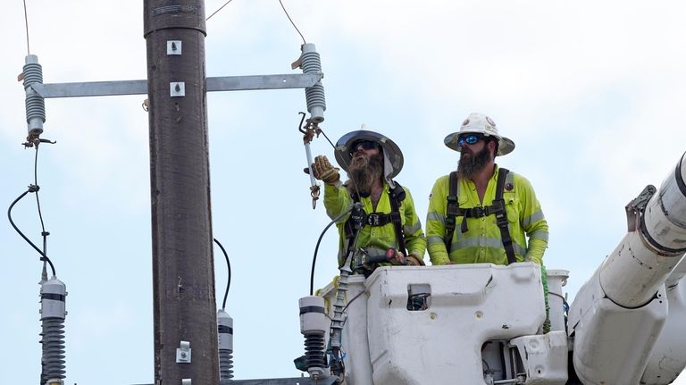 Workers repair a power line on Thursday, June 29, 2023,...