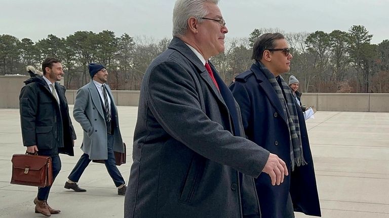 Former U.S. Rep. George Santos, right, leaves federal court with...