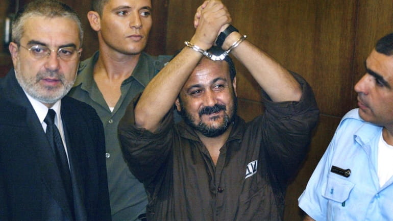 Marwan Barghouti, center, raises his handcuffed hands in the air...