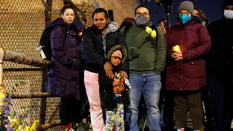 A woman and child cry while attending a vigil for...