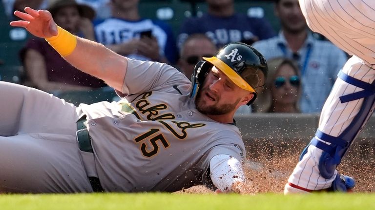 Oakland Athletics' Seth Brown, left, scores past Chicago Cubs catcher...