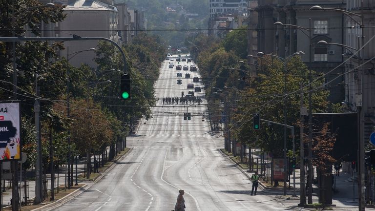 A woman crosses an empty street cordoned off by police...