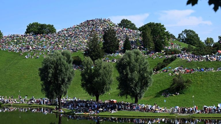 Fans sit on the Olympiaberg in the Olympiapark and wait...