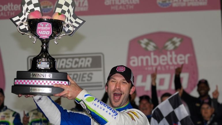 Daniel Suarez holds the trophy after winning the NASCAR auto...