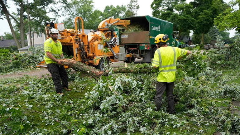 Work crews clean up Friday in Beverly Hills, Mich., after winds...
