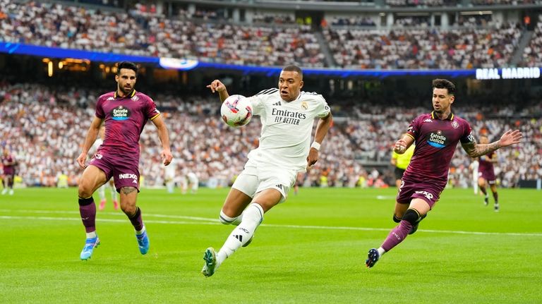 Real Madrid's Kylian Mbappe, centre, challenges for the ball with...