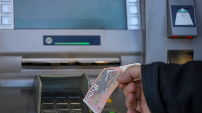 A man withdraws Serbian Dinars from a bank cash machine...