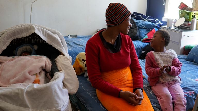 Mapule Radebe sits with her daughter Morello, right, and baby...