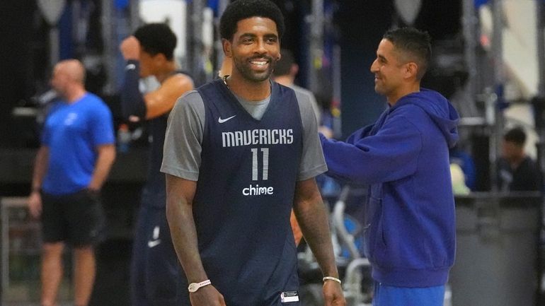 Dallas Mavericks guard Kyrie Irving smiles as he walks on...