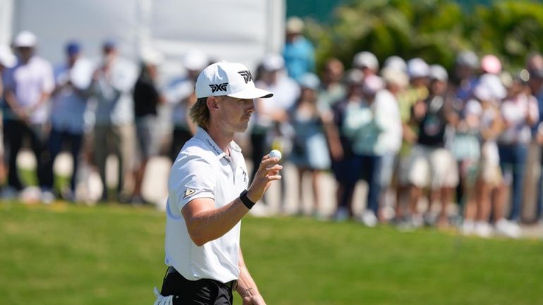 Jake Knapp, of the United States, holds up his ball...