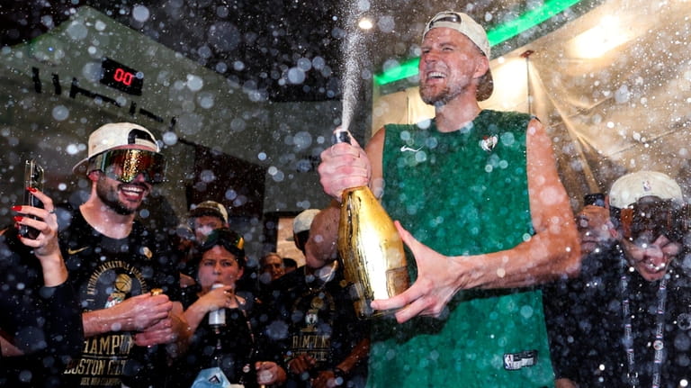 Boston Celtics center Kristaps Porzingis sprays champagne while celebrating after...