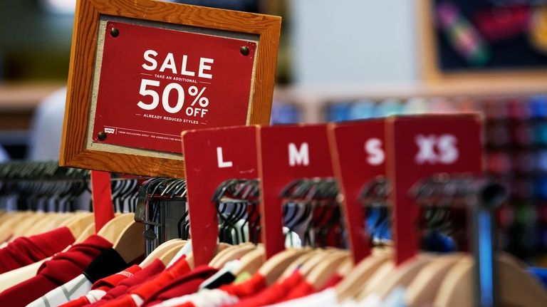 A sale sign is displayed on a rack of clothes...