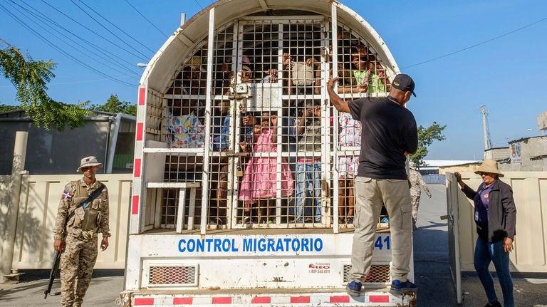 Haitians detained for deportation stand inside a police truck on...