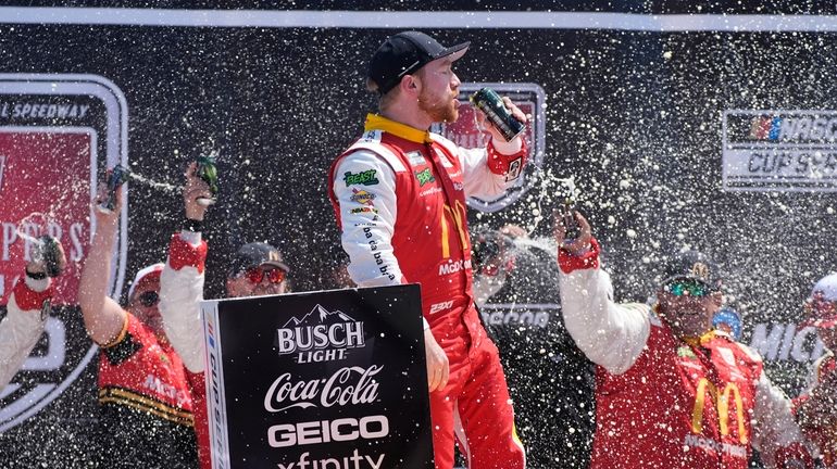 Tyler Reddick stands on his car after winning a NASCAR...