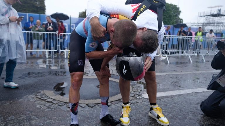 Remco Evenepoel, of Belgium, left, reacts after winning the men's...