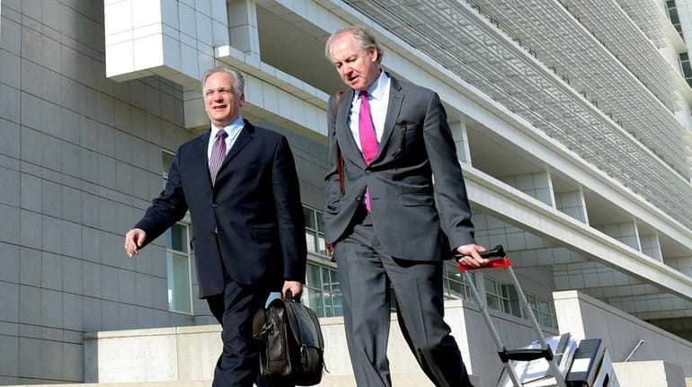 Edward Mangano, left, leaves the federal courthouse in Central Islip...