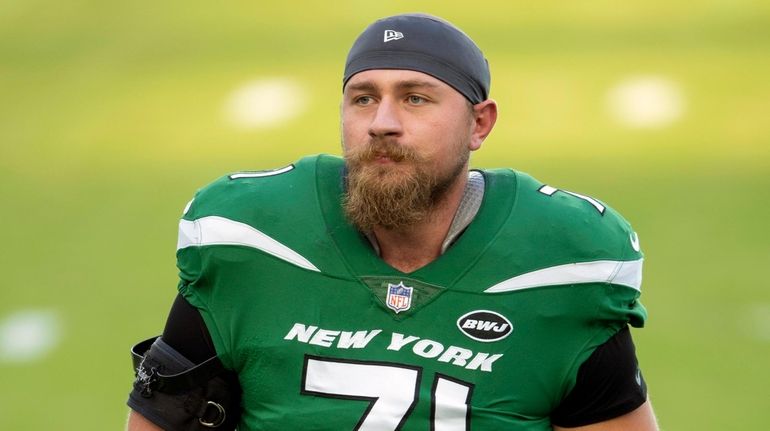 Jets offensive lineman Alex Lewis warms up on the field before...