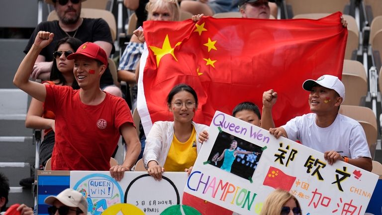 Supporters of China's Zheng Qinwen display a Chinese flag as...