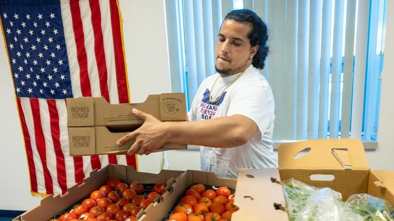 Darius Wilson, of North Amityville, moves produce from a truck onto...