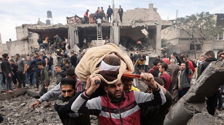 Palestinians evacuate a wounded woman following Israeli airstrikes in Khan...