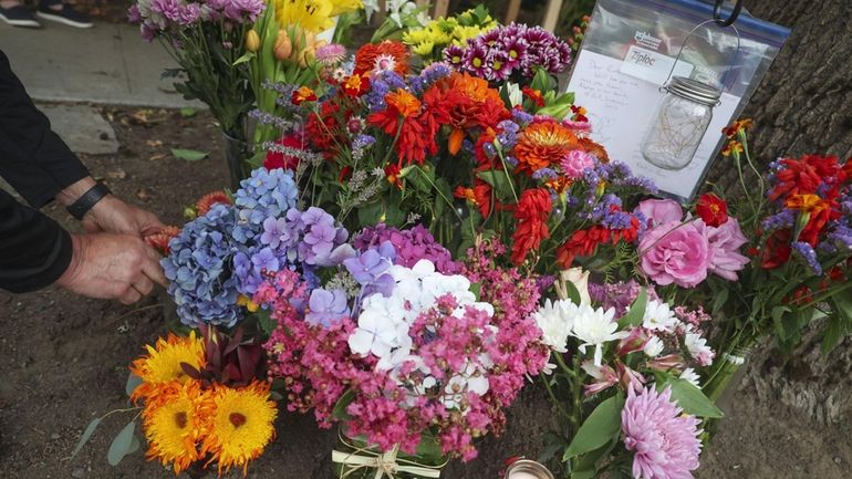 A visitor places flowers on a memorial for a beloved...