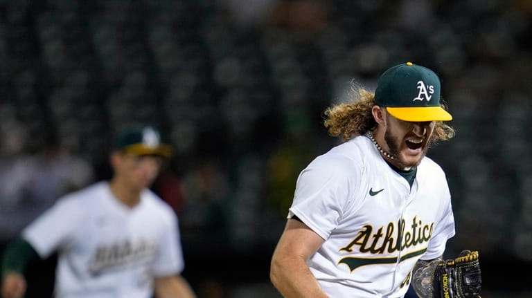 Oakland Athletics pitcher Joey Estes, right, reacts after striking out...