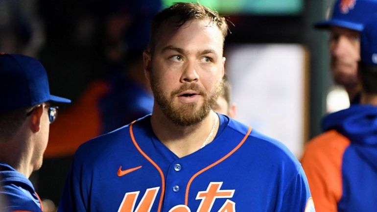 Mets starting pitcher Tylor Megill walks through the dugout after...