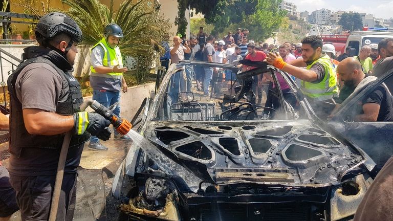 Civil Defense workers inspect the remains of a burned car...