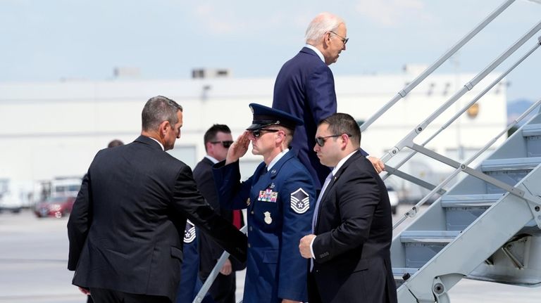 President Joe Biden walks up the steps of Air Force...