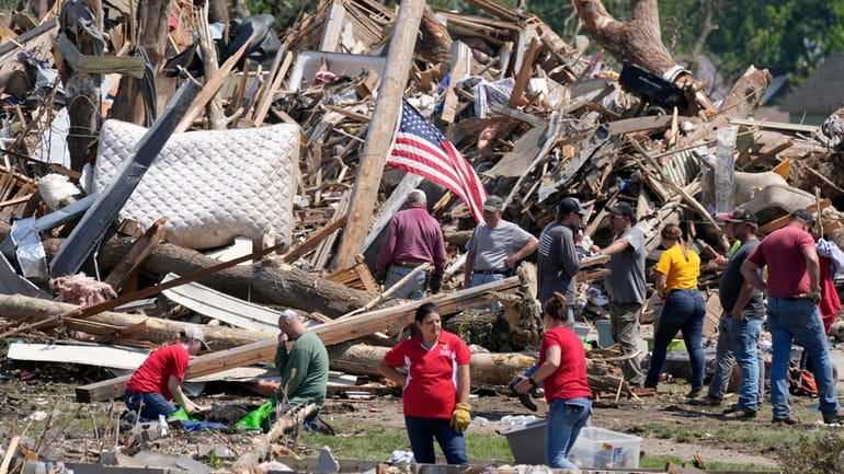 Local residents clean up debris from a tornado damaged home,...
