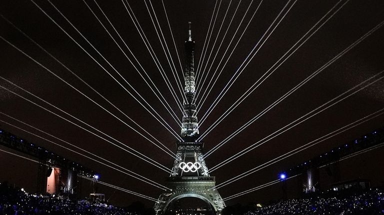 A light show is projected from the Eiffel Tower in...