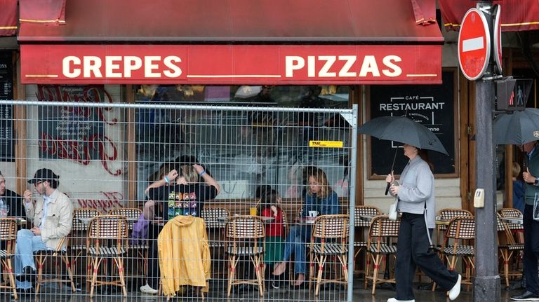 Patrons sit outside a restaurant behind a remaining security barrier...