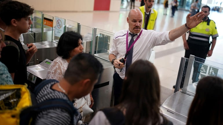Employees try to give directions to passengers crowded at the...