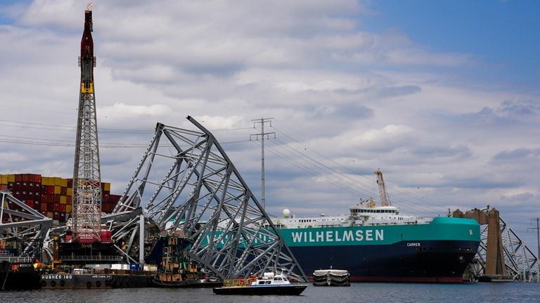 A vessel, center right, moves past the stranded container ship...