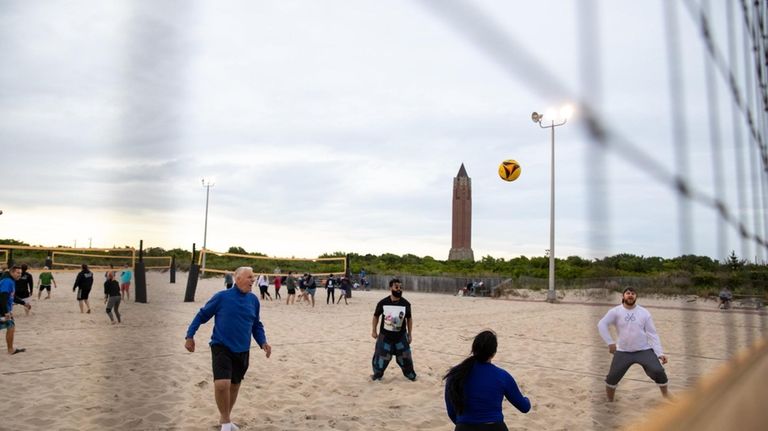 Beachgoers play volleyball near sundown at Jones Beach in Wantagh,...