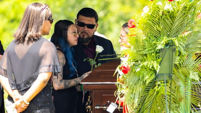 Alexis Nungaray places a white rose on the casket of...