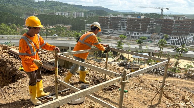 Workers are seen at a construction site in the new...