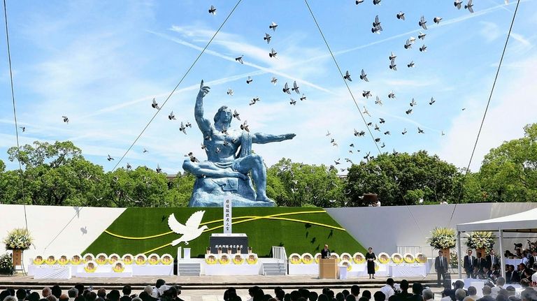 Doves fly over the Peace Statue during a ceremony to...