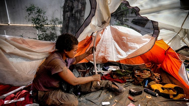 Suffering from homelessness Esca Guernon fixes her tent that's set...